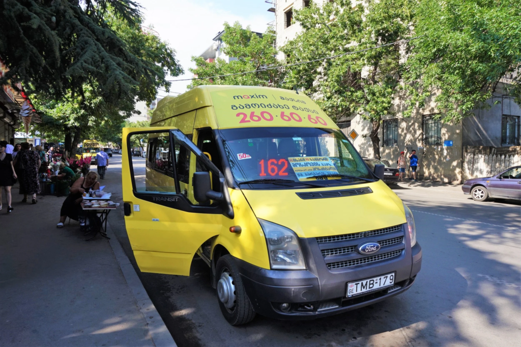 Random photo of famous Tbilisi marshrutka. It is yellow minibus on photo and the door is opened to take a passenger.